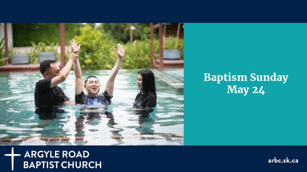 a young man with a big smile being lowered for baptism in a swimming pool. by his pastor. A woman is watching.