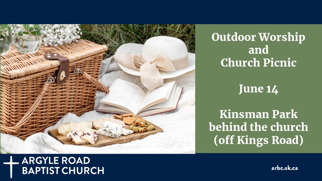 picnic basket with assortment of cheeses on a board on a cloth, and a sunhat. Flowers on the basket.